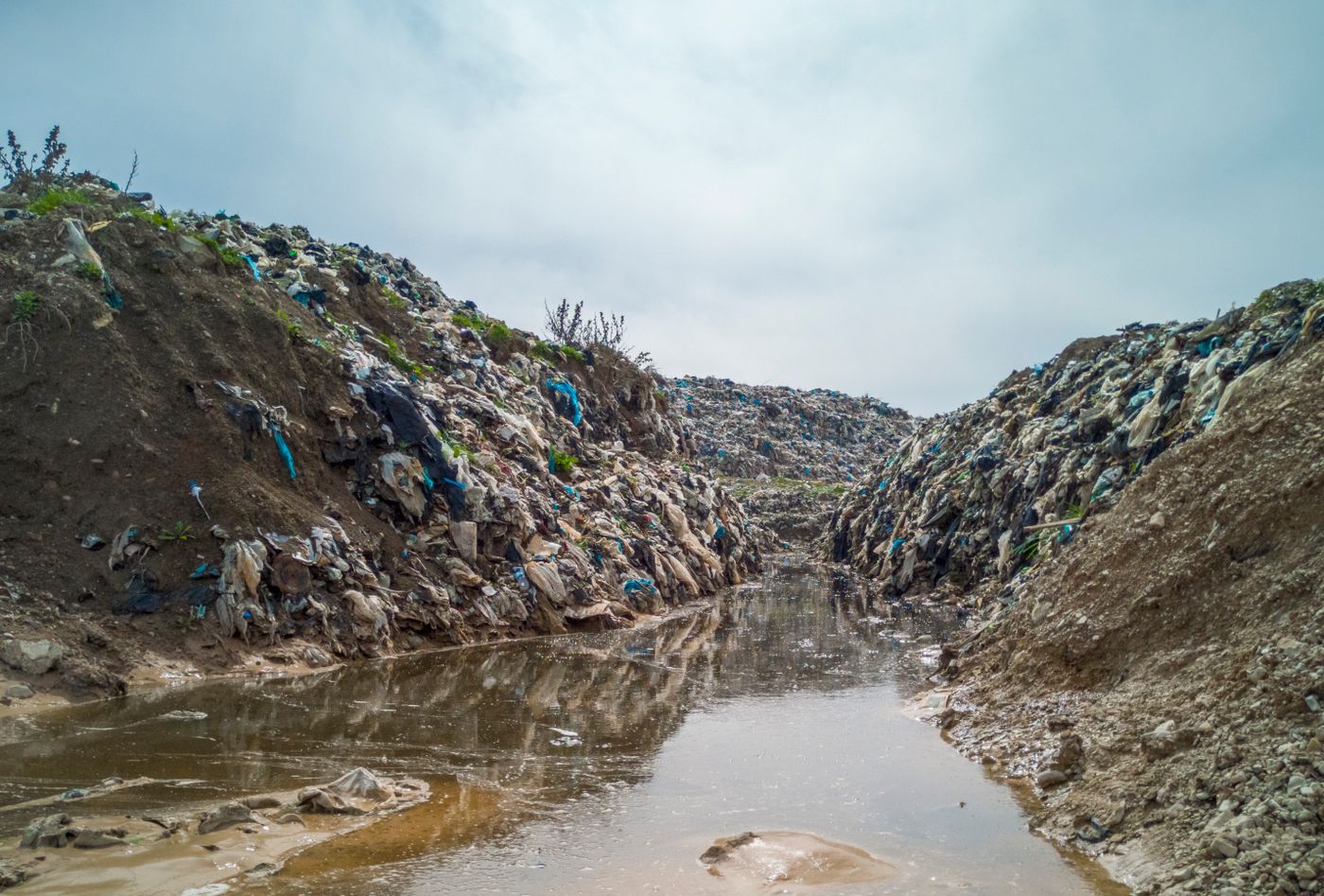 A river channel lined with rubbish and plastic waste
